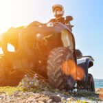 Jazdec na štvorkolke s prilbou a ochranným vybavením jazdiaci v náročnom teréne.